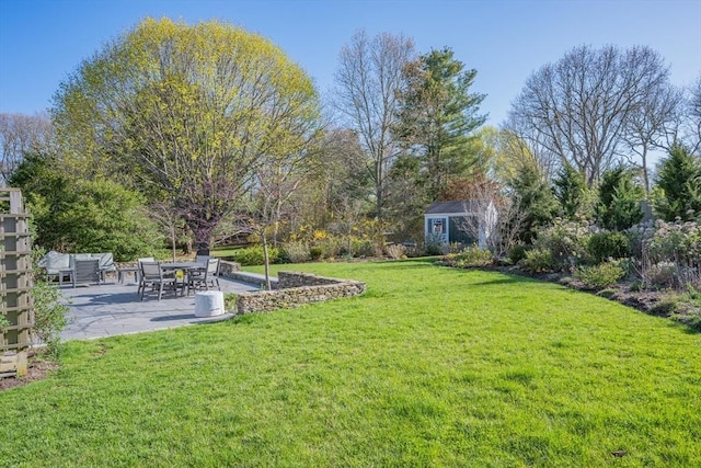 view of green lawn with a patio area, a shed, and an outbuilding