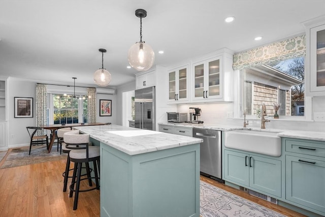 kitchen featuring appliances with stainless steel finishes, a sink, a center island, recessed lighting, and decorative light fixtures
