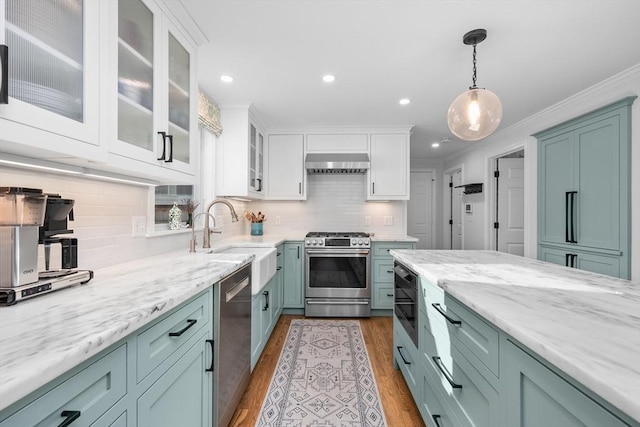 kitchen with appliances with stainless steel finishes, wall chimney range hood, white cabinets, backsplash, and recessed lighting