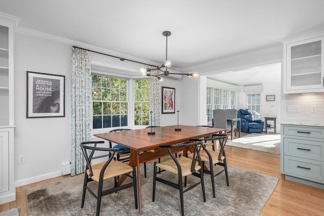 dining area featuring a chandelier, ornamental molding, light wood-style flooring, and baseboards