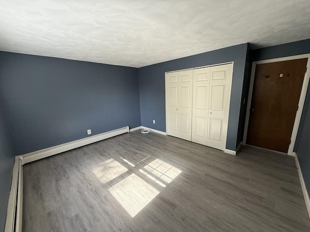 924 Main St Unit 26, Woburn, MA 01801 - unfurnished bedroom featuring wood finished floors, a closet, a textured ceiling, and a baseboard heating unit