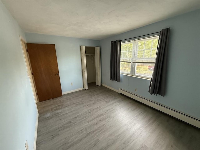 924 Main St Unit 26, Woburn, MA 01801 - unfurnished bedroom featuring a baseboard heating unit, wood finished floors, and a closet