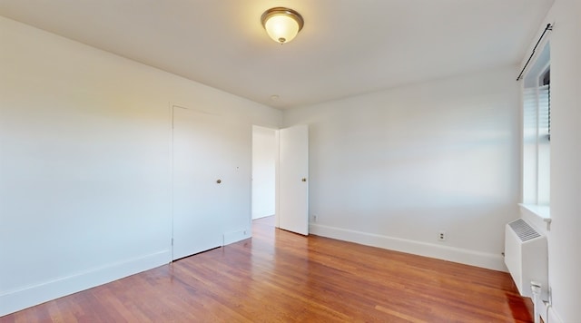 unfurnished room featuring radiator and hardwood / wood-style floors