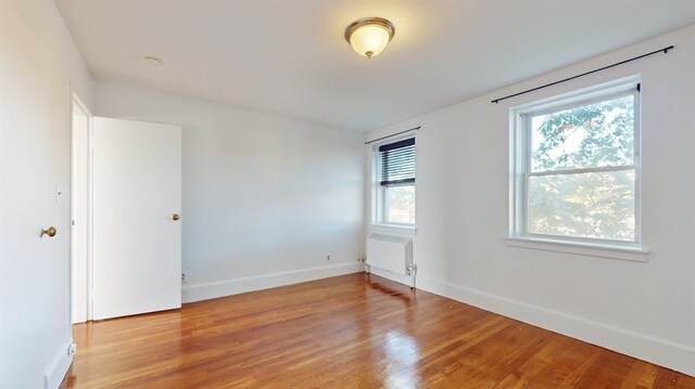 unfurnished room featuring radiator and light hardwood / wood-style flooring