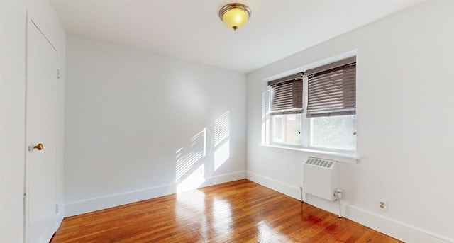 empty room featuring wood-type flooring and radiator