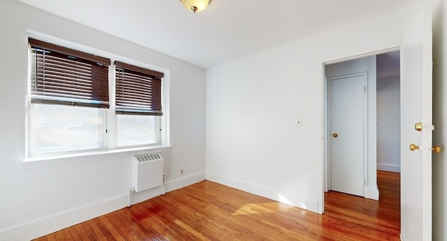 unfurnished bedroom with radiator heating unit and hardwood / wood-style floors