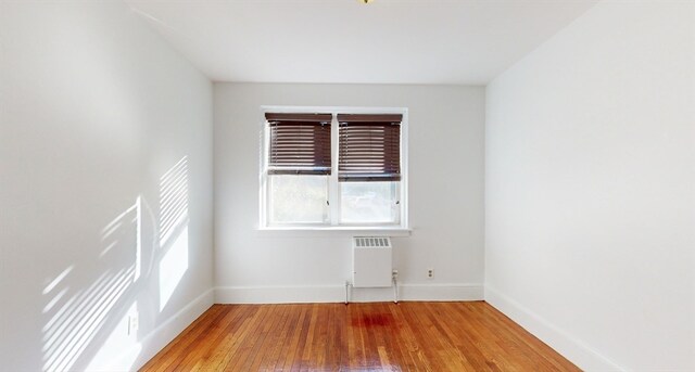 empty room featuring hardwood / wood-style flooring and radiator heating unit