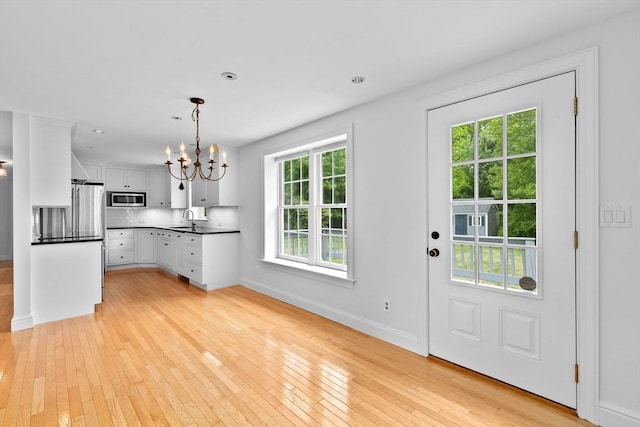 258 Plympton Rd, Plymouth, MA 02360 - kitchen with stainless steel appliances, a chandelier, dark countertops, light wood-style flooring, and baseboards