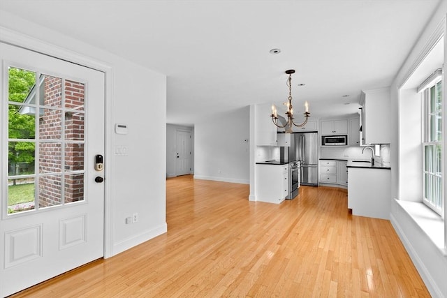 258 Plympton Rd, Plymouth, MA 02360 - kitchen featuring appliances with stainless steel finishes, a chandelier, dark countertops, light wood-type flooring, and open floor plan