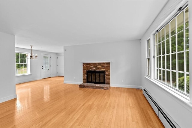 258 Plympton Rd, Plymouth, MA 02360 - unfurnished living room with baseboard heating, a chandelier, light wood-type flooring, a brick fireplace, and baseboards