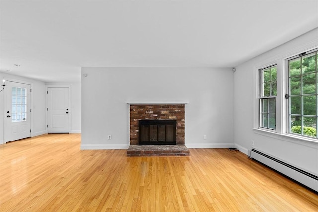 258 Plympton Rd, Plymouth, MA 02360 - unfurnished living room with a baseboard radiator, light wood-type flooring, a brick fireplace, and baseboards