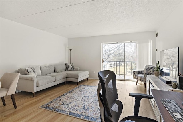 living area with visible vents, light wood-type flooring, and a textured ceiling