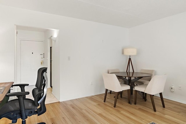 dining space featuring baseboards and light wood finished floors