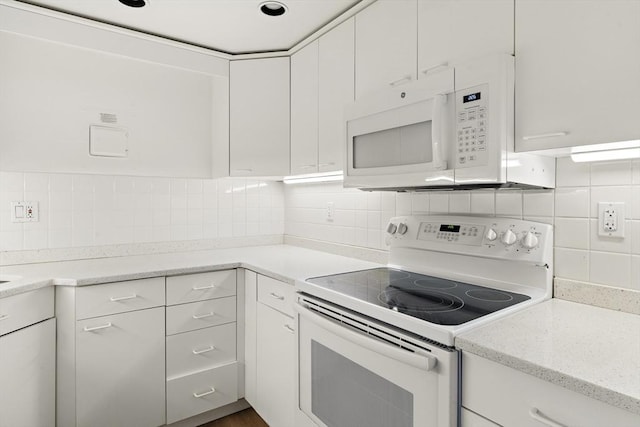 kitchen featuring light stone counters, decorative backsplash, white cabinets, and white appliances