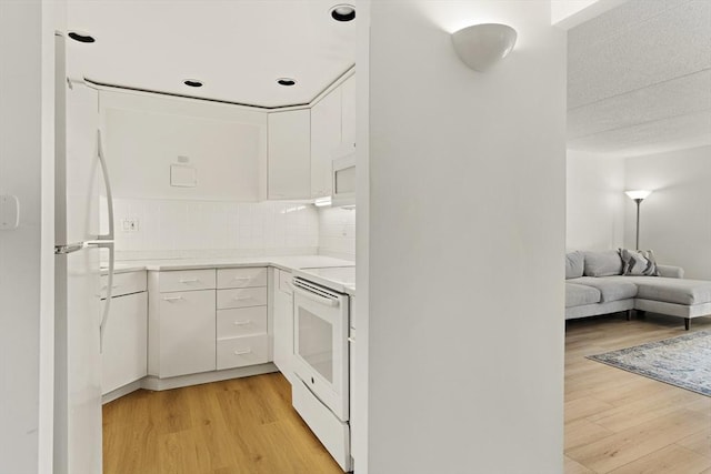 kitchen with white appliances, light countertops, light wood-style floors, white cabinetry, and tasteful backsplash