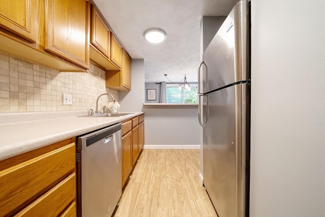 27 Mason Ct Unit 27, Amesbury, MA 01913 - kitchen with stainless steel appliances, a sink, light wood-style flooring, backsplash, and light countertops