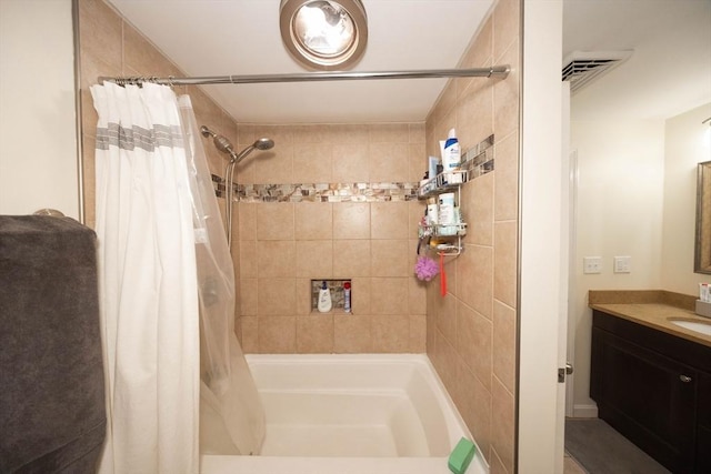 bathroom with visible vents, tiled shower, and vanity