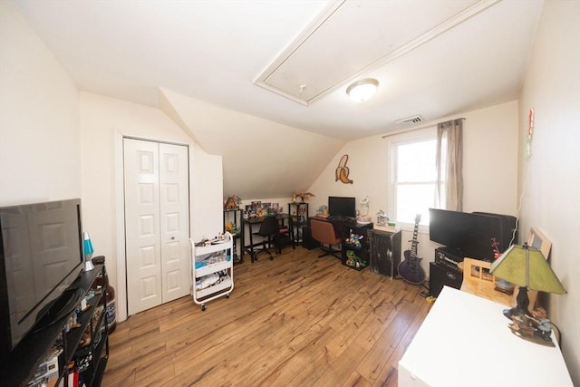 office space with light wood finished floors, visible vents, attic access, and vaulted ceiling