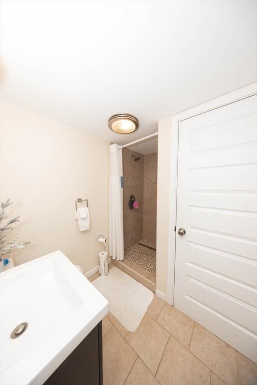 bathroom featuring vanity, a shower stall, baseboards, and tile patterned floors