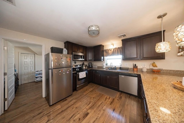 kitchen with dark brown cabinets, light wood-style floors, appliances with stainless steel finishes, and a sink