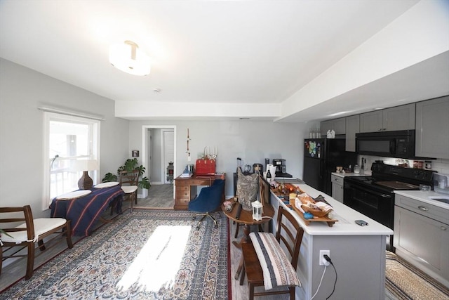 kitchen with black appliances, light countertops, a kitchen island, and gray cabinetry