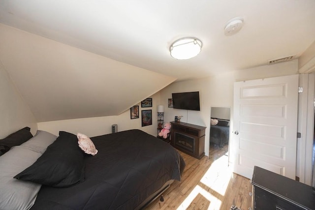 bedroom with visible vents, lofted ceiling, and light wood finished floors