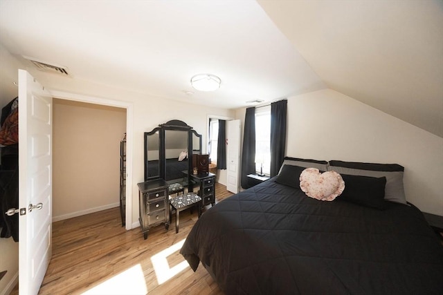 bedroom featuring visible vents, baseboards, lofted ceiling, and light wood-style floors