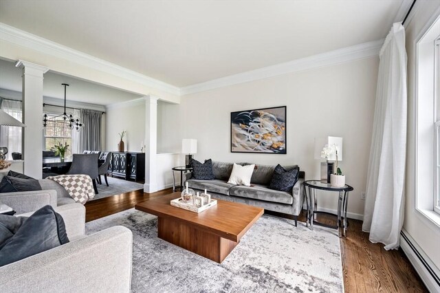86 Pioneer Trl, Plymouth, MA 02360 - living room featuring decorative columns, a baseboard heating unit, crown molding, wood finished floors, and a chandelier