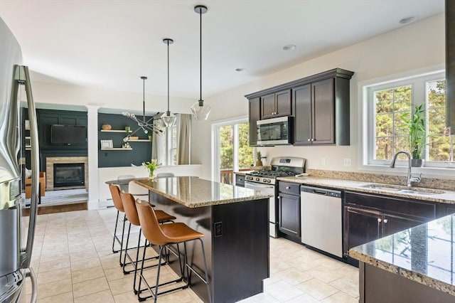 86 Pioneer Trl, Plymouth, MA 02360 - kitchen featuring appliances with stainless steel finishes, a sink, light stone countertops, a center island, and decorative light fixtures