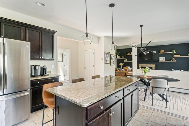 86 Pioneer Trl, Plymouth, MA 02360 - kitchen featuring freestanding refrigerator, light tile patterned floors, a kitchen island, light stone countertops, and dark brown cabinets