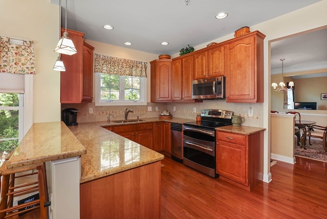 kitchen featuring kitchen peninsula, decorative light fixtures, a chandelier, stainless steel appliances, and a wealth of natural light