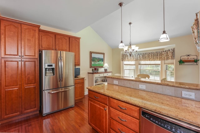 kitchen featuring wood-type flooring, vaulted ceiling, hanging light fixtures, appliances with stainless steel finishes, and light stone countertops