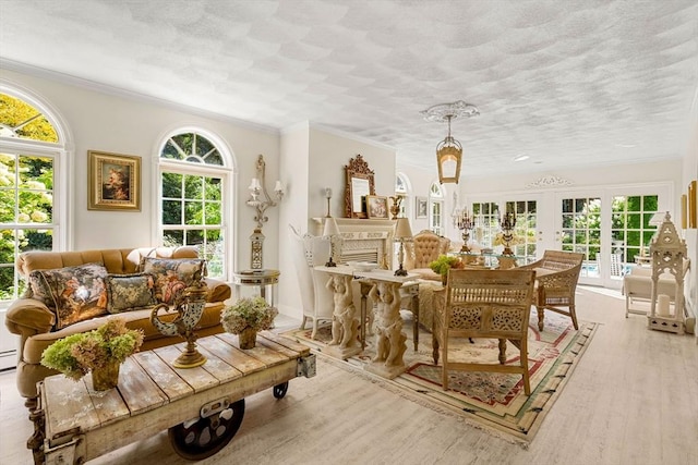 sitting room featuring ornamental molding, wood finished floors, a textured ceiling, and french doors