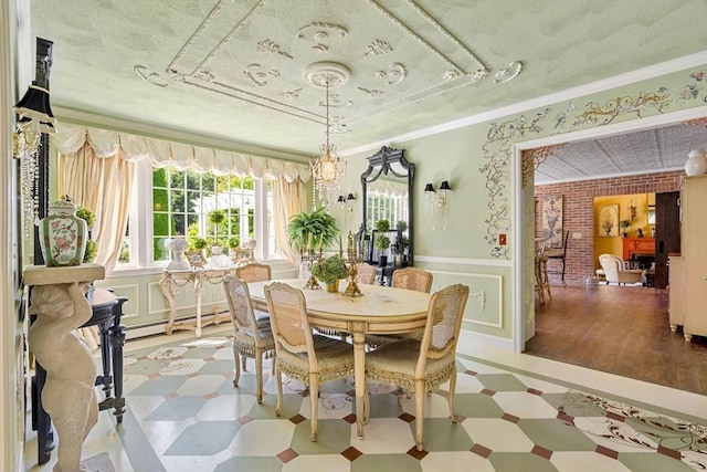 dining area with light floors, wainscoting, a chandelier, ornamental molding, and a baseboard radiator