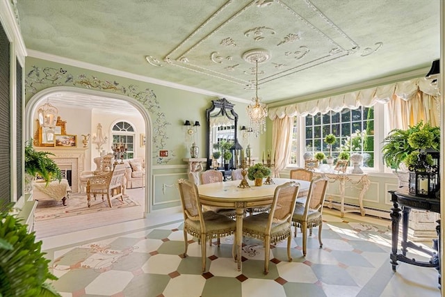 dining space with light flooring, baseboard heating, wainscoting, a textured ceiling, and arched walkways