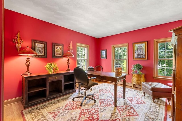 office area with healthy amount of natural light, wood finished floors, and baseboards