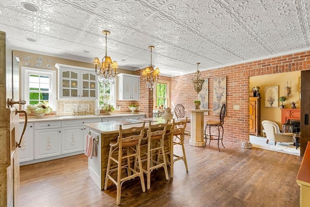 kitchen with a chandelier, a sink, light wood-type flooring, an ornate ceiling, and light countertops