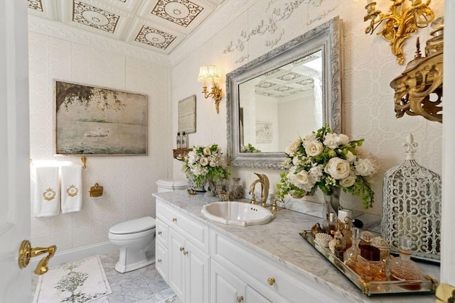 bathroom featuring toilet, vanity, marble look tile flooring, coffered ceiling, and baseboards