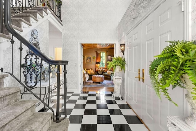 entrance foyer with stairway, tile patterned floors, and a towering ceiling