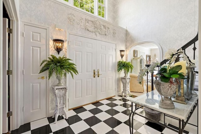 entryway featuring a towering ceiling, tile patterned floors, and arched walkways