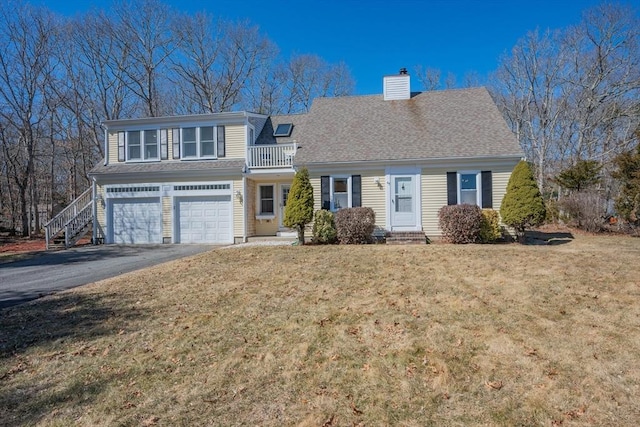 view of front of house with driveway, an attached garage, a shingled roof, a chimney, and a front lawn