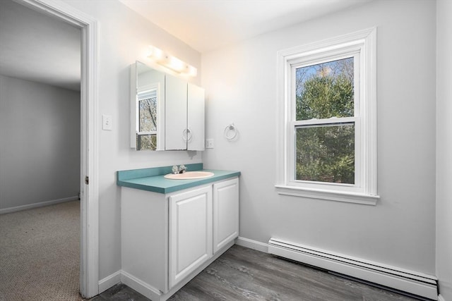 bathroom with vanity, a baseboard heating unit, and baseboards