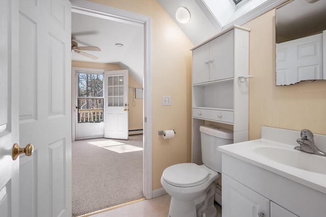 bathroom featuring ceiling fan, toilet, vaulted ceiling, baseboard heating, and vanity