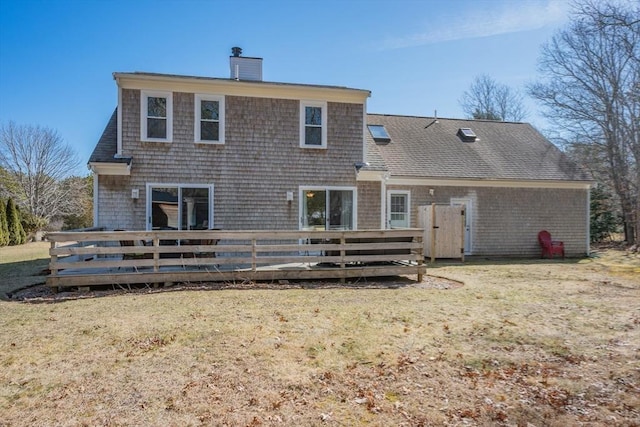 rear view of house featuring a wooden deck, a chimney, a yard, and roof with shingles