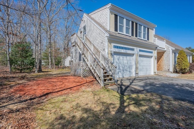 view of front facade with stairway, a garage, driveway, and a shingled roof