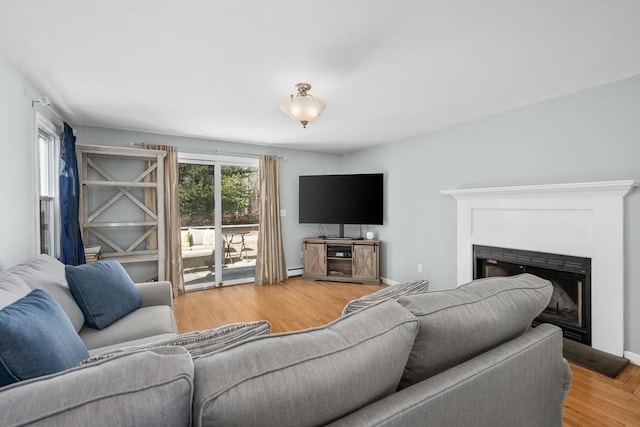 living room with baseboard heating, a fireplace, and light wood finished floors