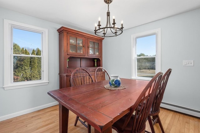 dining room featuring an inviting chandelier, a healthy amount of sunlight, light wood-type flooring, and baseboards