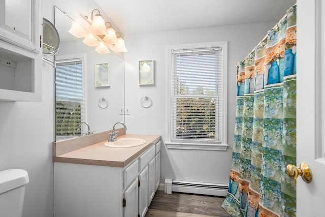 full bathroom featuring wood finished floors, toilet, vanity, and a baseboard radiator