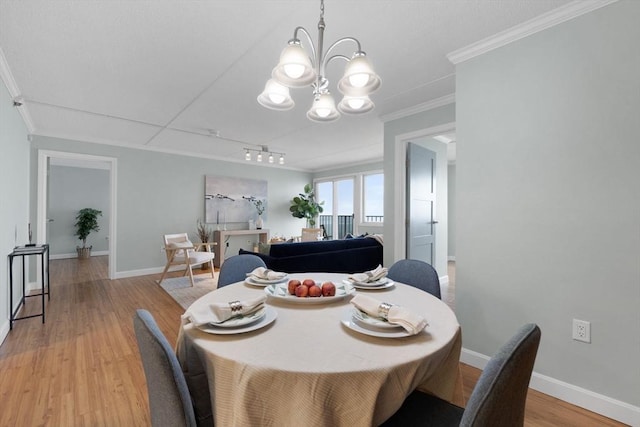 dining room featuring baseboards, light wood-style floors, an inviting chandelier, and crown molding