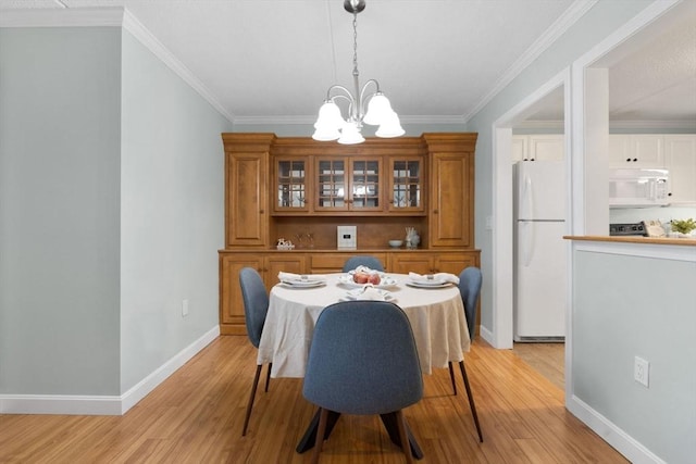 dining space with baseboards, a chandelier, crown molding, and light wood-style flooring